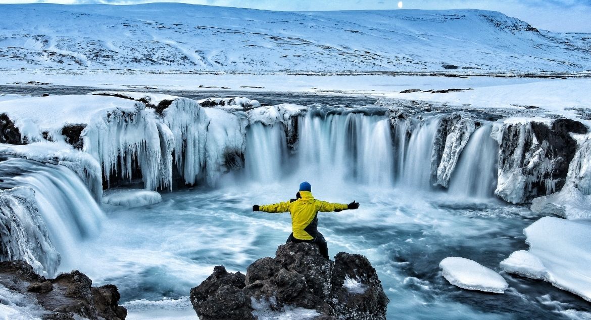 Homem na cascata Godafoss, na Islândia