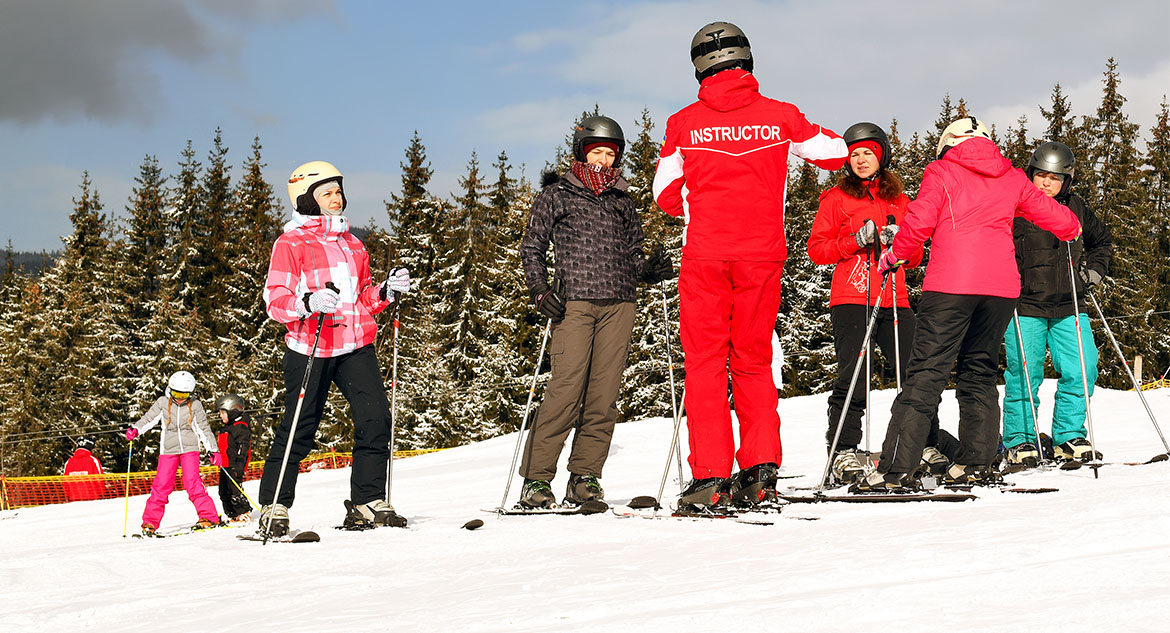 Instrutor ensinando esquiadores iniciantes