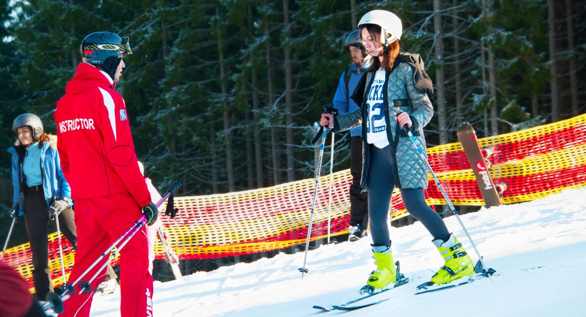 Menina fazendo aulas de esqui com instrutor