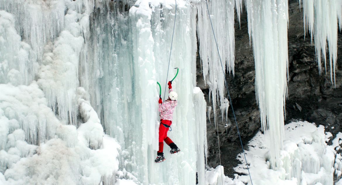 Esportista escalando cachoeira congelada