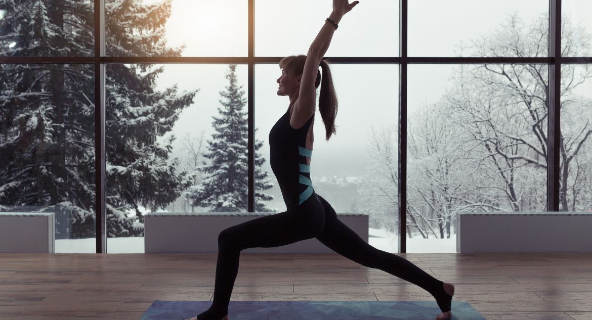 Mulher praticando yoga com cenário de neve ao fundo